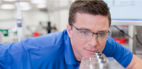 Man in safety glasses examining machine